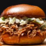 Cooked low and slow in smoky goodness, pulled and lightly sauced, Queology's pork sandwich is topped with a creamy, crunchy slaw.